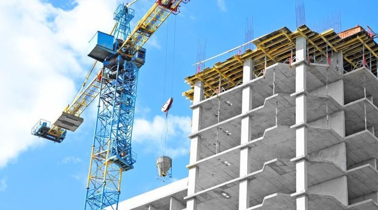 Crane and building under construction against blue sky